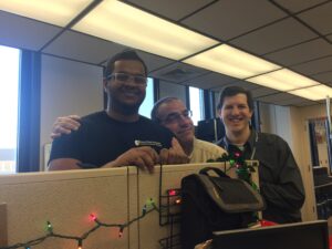 Basile, a colleague and a student outside his cubicle. 